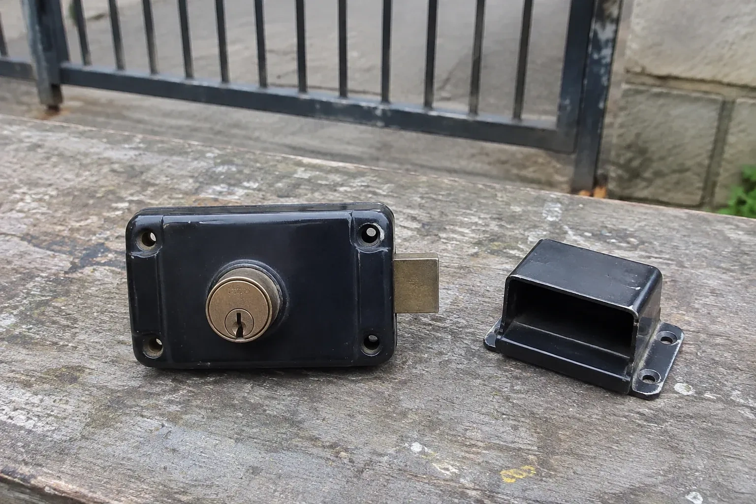 Detached rim gate lock and separate box keeper on an outdoor workbench. — Gate & Building Entry Locks, Port Colborne