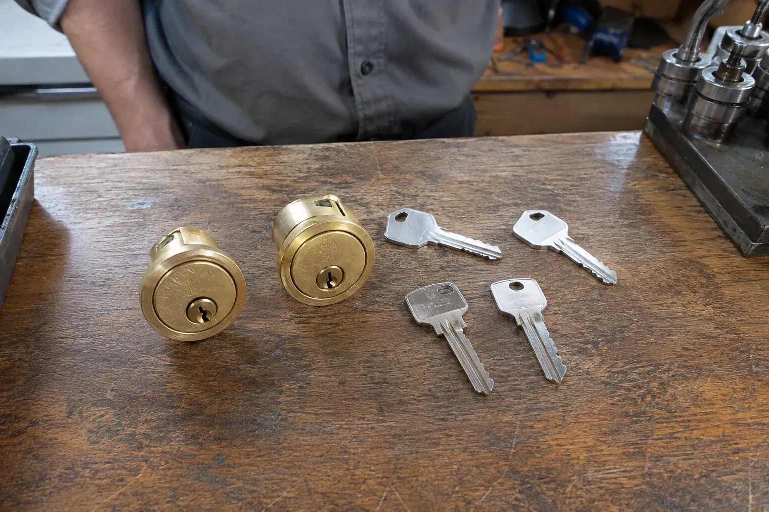 Two detached brass lock cylinders and four house keys on a wooden counter. — Lock Rekeying, Port Colborne